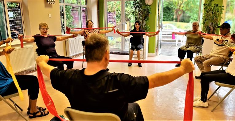 A group sat in a circle, stretching resistance bands