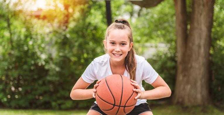 Child holding a basketball on the court