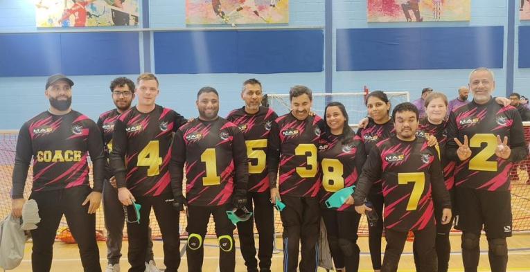 Team photo of a group of blind and visually impaired people at an indoor sports hall