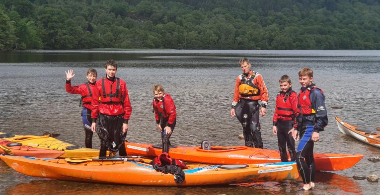 Children and instructors on canoes on water in the Scottish Highlands
