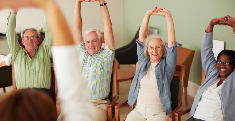 Four older people participate in seated exercise session