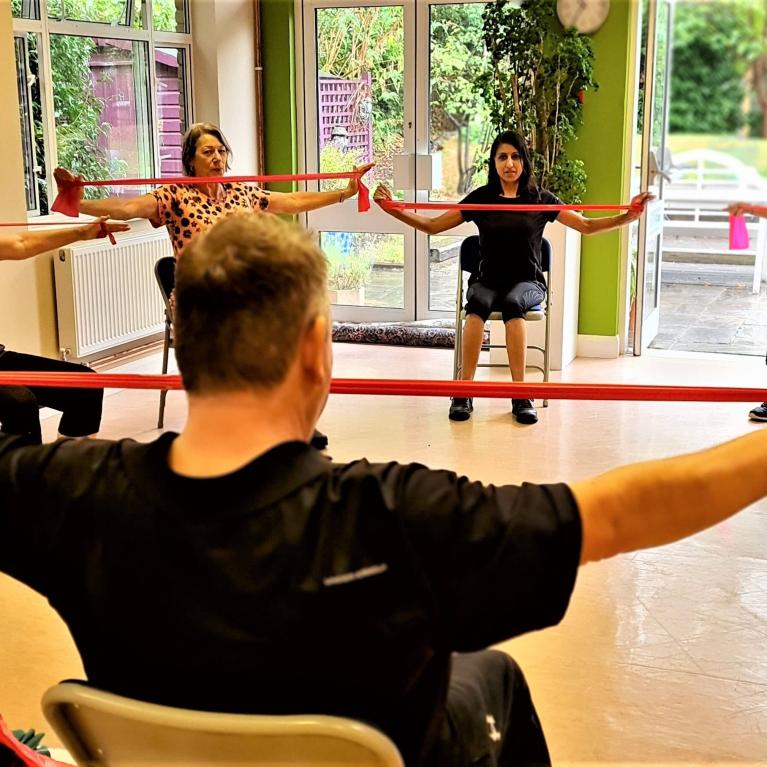 A group sat in a circle, stretching resistance bands