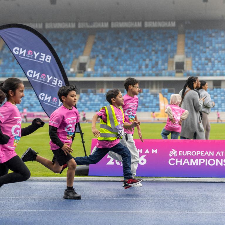 Four children running on the track at Alexander Stadium in Birmingham