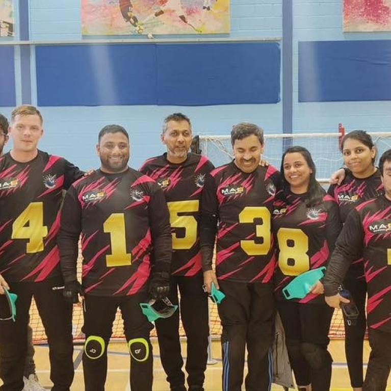 Team photo of a group of blind and visually impaired people at an indoor sports hall