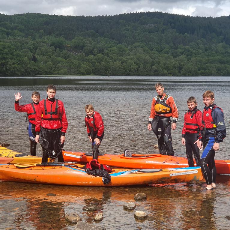 Children and instructors on canoes on water in the Scottish Highlands