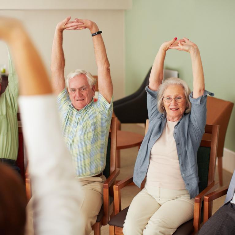 Four older people participate in seated exercise session