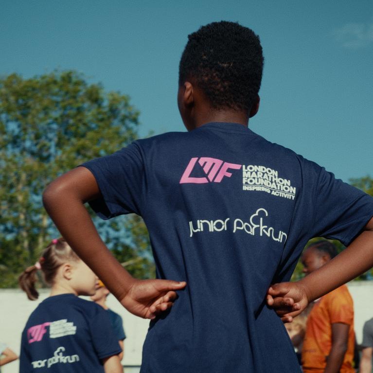Child at junior parkrun wearing a t-shirt with junior parkrun and London Marathon Foundation logos