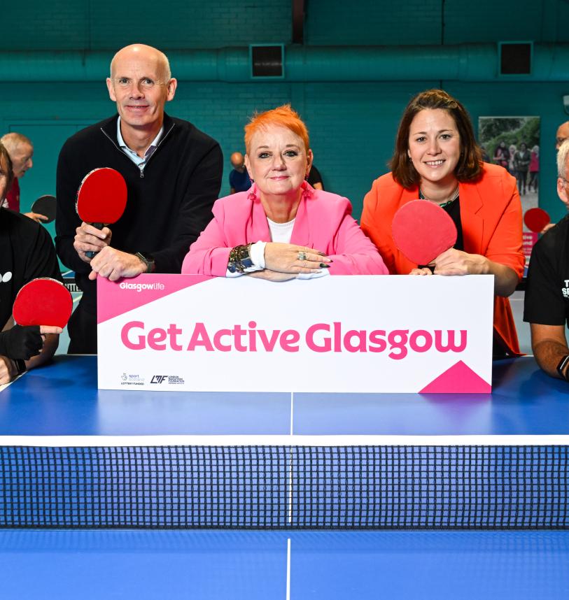 Five people standing at one end of a table tennis table around a Get Active Glasgow sign